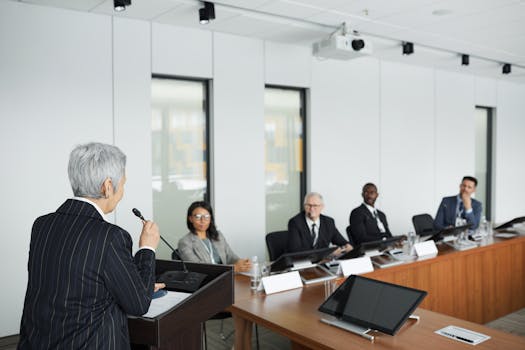 A diverse group of professionals engaging in a business meeting in a conference room with a speaker at the podium.